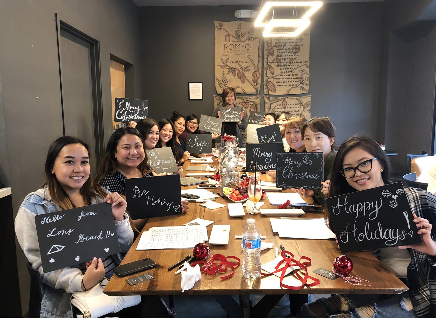 Workshop guests holding up their finished calligraphy chalkboard pieces at the Romeo Chocolates opening